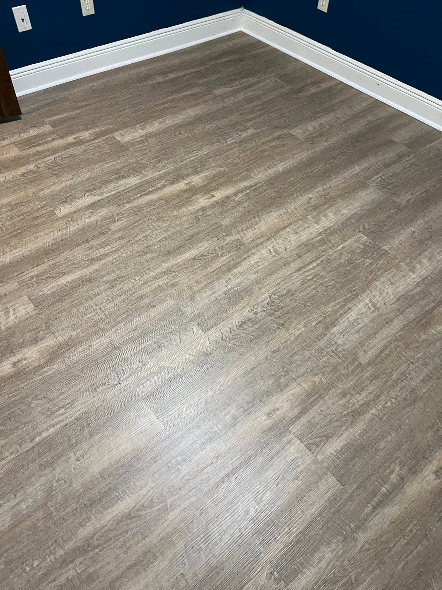 Gray plank flooring installation with crisp white trim